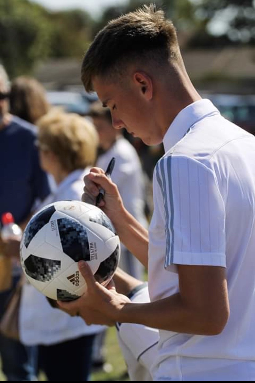 Young football manager signs autographs